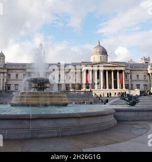 London, Greater London, England, Oktober 05 2021: Wasser fließt aus einem Brunnen am Trafalgar Square, während Touristen an der National Gallery in der BA vorbeilaufen Stockfoto