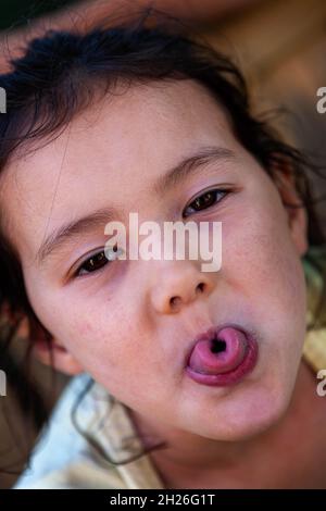 Junge englische/thailändische Mädchen, die aus einer gewellten Zunge herausragt Stockfoto