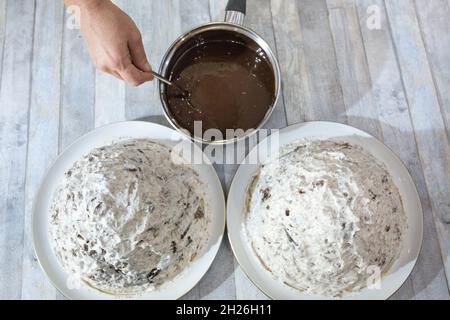 Ein Schritt-für-Schritt-Prozess für die Herstellung einer sauren Sahneschokolade Kuchen. Der geformte Kuchen wird mit flüssigem Schokoladeneier gegossen. Stockfoto