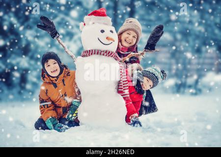 Mutter und ihre Kinder spielen im Winterpark Stockfoto