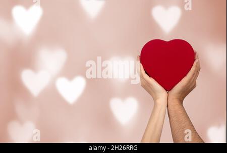 Paare halten herzförmige Geschenkbox mit Bokeh Hintergrund. Liebe, Geschenk und gegenwärtiges Konzept. Stockfoto