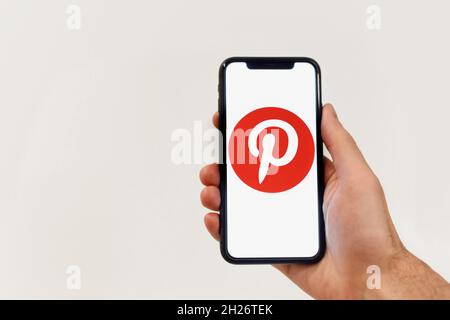 Minsk, Weißrussland - 20. Oktober 2021: Mann Hände halten iphone mit Pinterest Apps Logo auf isoliert auf weiß Stockfoto