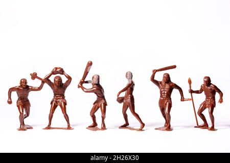 Große Spielzeugfiguren von primitiven Menschen auf weißem Hintergrund Stockfoto