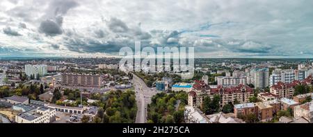 Herbstliche Stadt Luftpanorama von Klochkivskyj Abstieg auf Lopan Flussgebiet. Dachgebäude und Straßen mit epischer Wolkenlandschaft in Kharkiv, Ukraine Stockfoto