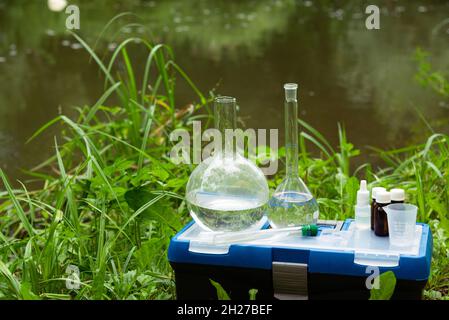 Wasserprobenahme. Eine Reihe von Kolben auf dem Hintergrund des Flusses. Laborant nimmt Wasserproben. Stockfoto