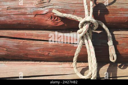 An einem sonnigen Tag hängt an einer Holzwand ein geknüpftes raues Seil Stockfoto