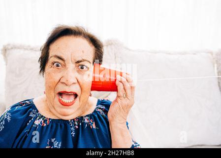 Überraschte eine ältere Frau, die einem Telefon zuhörte Stockfoto