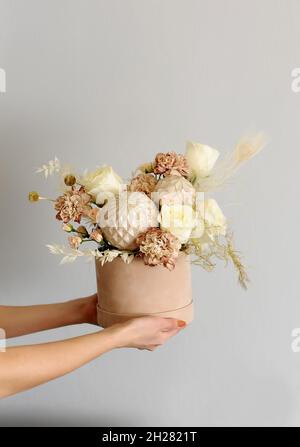 Blumen für Valentinstag. Florale Komposition. Frisches Geschenk von Bouquet und Urlaubsdekor: Kugeln, getrocknete Blumen in den Händen einer Floristin Frau. Cylindri Stockfoto