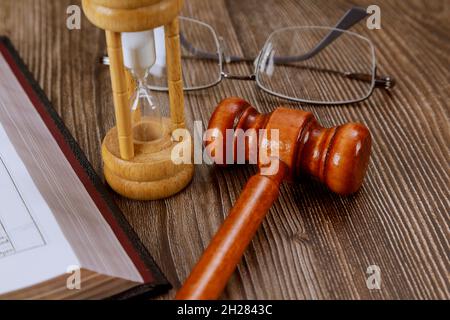 Öffne das Heilige Bibelbuch mit dem Sanduhr-Richtergavel auf hölzernem Hintergrund Stockfoto