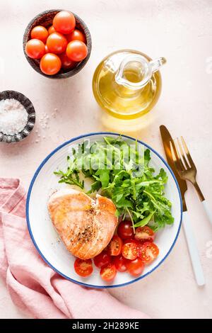 Rosafarbenes Thunfischsteak mit Rucola und Tomaten. Gesunde, ausgewogene Mahlzeit Stockfoto