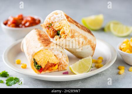 Frühstück vegetarische Burrito Wrap mit Omelette und Gemüse auf einem Teller. Tortilla Wrap Sandwich Stockfoto