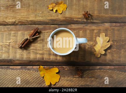 Eine Tasse Kürbiskaffee mit Gewürzen auf einem Holzhintergrund. Herbststimmung. Zeit für heiße Getränke. Draufsicht. Stockfoto
