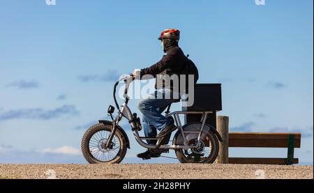 Mann auf einem Mountainbike mit dicken Reifen und Helm in einem Park. Fat Bike. Stockfoto