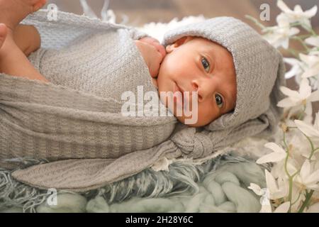 6 Monate alte kleine süße arabische muslimische Mädchen legen und posieren auf bequeme Wolle niedliches Gesicht Draufsicht Portrait grau weichen Schal Stockfoto
