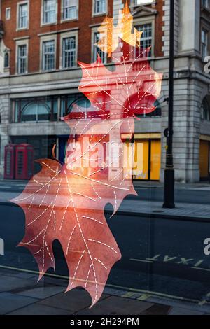 Schaufensterauslage, Fortnum & Mason, das gehobene Kaufhaus in Piccadilly, London; Herbstblätter spiegeln die Straße dahinter wider Stockfoto