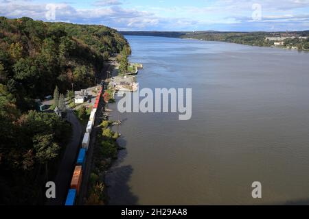 Der Blick auf einen Güterzug fährt entlang des Hudson River auf der Highland-Seite mit der Küste von Poughkeepfie im Hintergrund vom Gehweg über die Hudson Fußgängerbrücke, Highland.New York.USA Stockfoto