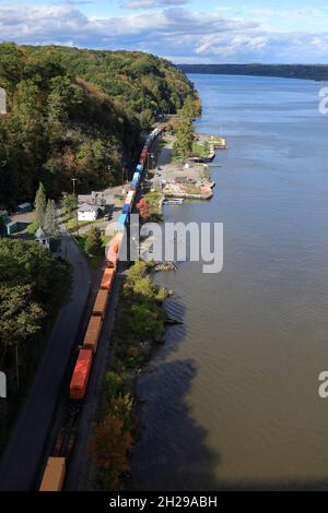 Der Blick auf einen Güterzug fährt entlang des Hudson River auf der Highland-Seite mit der Küste von Poughkeepfie im Hintergrund vom Gehweg über die Hudson Fußgängerbrücke, Highland.New York.USA Stockfoto