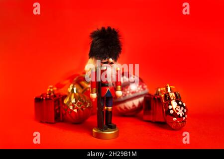 weihnachts-Nussknacker-Figur mit Dekorationen auf rotem Hintergrund. Stockfoto