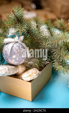 Weihnachtsspielzeug in einer Schachtel auf dem Hintergrund des Weihnachtsbaums. Stockfoto