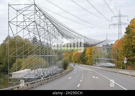 Ein großes Gerüst mit Sicherheitsnetz zum Schutz des Straßenverkehrs aufgrund von Arbeiten an einer Hochspannungsleitung und den Strommasten. Stockfoto