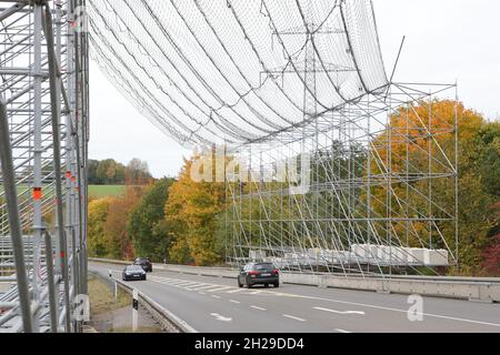 Ein großes Gerüst mit Sicherheitsnetz zum Schutz des Straßenverkehrs aufgrund von Arbeiten an einer Hochspannungsleitung und den Strommasten. Stockfoto