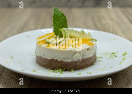Herzhafte Limettenkuchen mit Glasur, Limettenscheibe und Minzblatt. Stockfoto