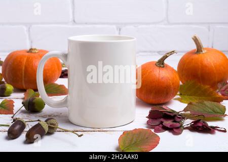 Weißer Kaffeebecher mit Danksagung, Kürbissen, Herbstblättern und Eicheln. Leerer Becher als Design-Promotion. Stockfoto