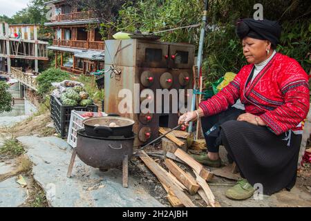 21. Oktober 2021 - Longji, China: Rote Yao-Frau, die im Dorf Tiantouzhai, Longji, Lebensmittel verkauft Stockfoto