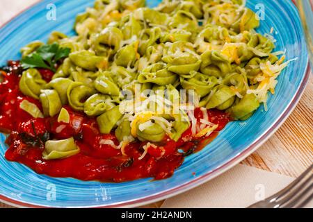 Grüne Tortellini mit gebackenem roten Paprika in Tomatensauce Stockfoto