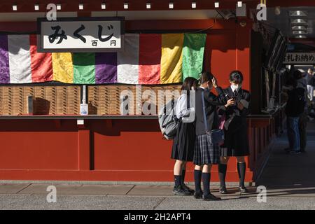 Tokio, Japan. Oktober 2021. Studenten lesen ihr Vermögen, nachdem sie im Senso-Ji-Tempel in Asakusa, Tokio, Mikuji gekauft hatten.Nachdem der mit der Pandemie von Covid-19 verbundene Ausnahmezustand am 30. September aufgehoben wurde, kehren die Besucher zu Tokyos touristischem Hotspot in Asakusa zurück. Kredit: SOPA Images Limited/Alamy Live Nachrichten Stockfoto