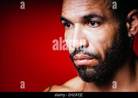 Gesicht mit einem Bart und einem Ohrring im Ohr eines kubanischen Mannes aus der Nähe. Studioportrait eines brutalen Mannes. Stockfoto