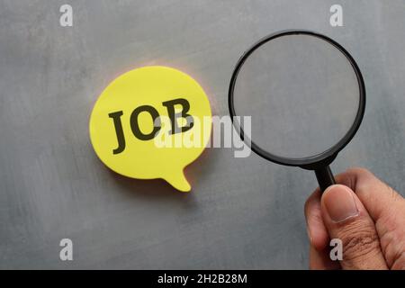 Offene Stelle, auf der Suche nach einem Stellenkonzept. Lupe und Sprechblase mit Text-JOB von Hand halten Stockfoto