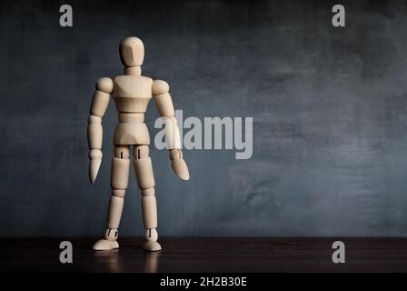 Menschliche Figur aus Holz, die im dunklen Raum steht. Platz für Text kopieren Stockfoto