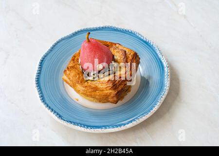 Rund fruchtiger Croissant mit kandierter Birne, Bitterschokolade und Haselnuss. Bereit zum Essen. Stockfoto