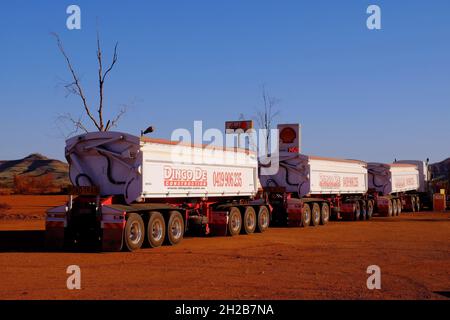 Straßenzug und rote Erde kurz vor Sonnenuntergang am Auski Roadhouse und Touristendorf im Outback in der Nähe des Karijini National Park, Pilbara, Westaustralien Stockfoto