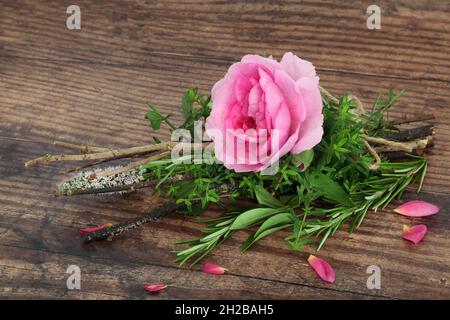 Heidnische Hexen bündeln Kräuter und Rosenblüten. Wird in magischen Liebetränke verwendet. Romantische Hexerei Zauberkonzept. Auf rustikalem Holzhintergrund. Stockfoto