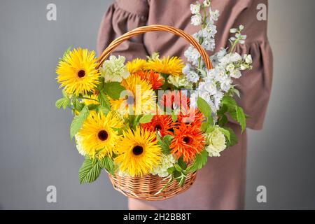 Blumenarrangement in Weidenkorb. Schöner Blumenstrauß in der Hand der Frau. Schönes frisches Bouquet. Kleiner Blumenladen und Lieferung von Blumen. Stockfoto