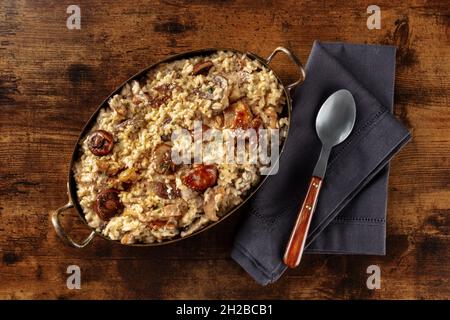Pilzrisotto, rustikaler Reis mit Pilzen, von oben auf dunklem Holzgrund geschossen Stockfoto