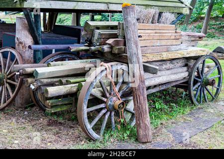 Alte verlassene hölzerne Bauernwagen mit Holzrädern, beladen mit Holzbalken und Pfosten Stockfoto