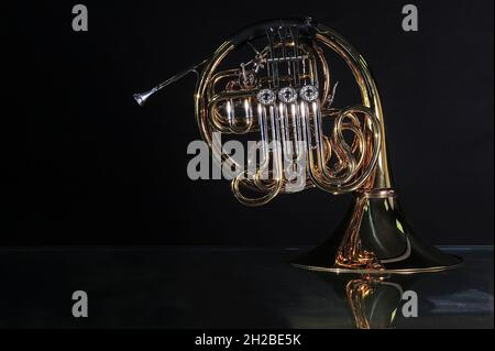 Goldenes französisches Horn mit weichem Licht isoliert auf schwarzem Hintergrund Stockfoto