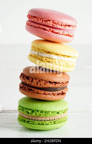 Vier fallende bunte Makronen auf weißem Holz rustikalen Hintergrund. Süße und bunte französische Kekse Makronen. Stockfoto