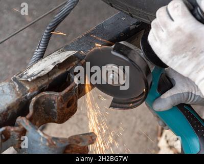 Nahaufnahme eines Arbeiters, der ein Metallstück von einer Anhängevorrichtung abschleifen soll Stockfoto