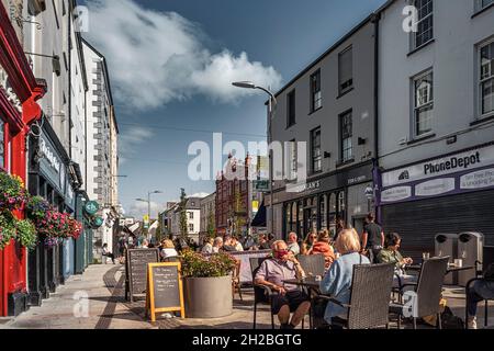 Leute, die draußen im Café (Pub) in der Fußgängerzone der Mall Street in der Stadt Tralee, der Haupteinkaufsstraße, sitzen. August. Tralee, co. Kerry, Irland. Stockfoto