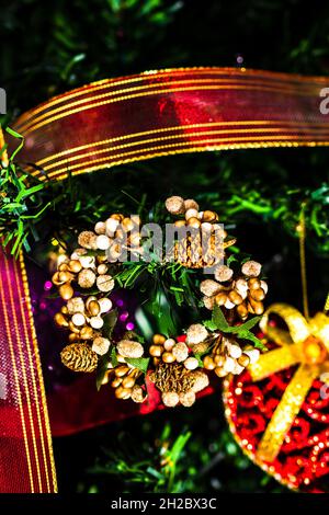 Vertikale Nahaufnahme eines Kranzes und Dekorationen, die an einem Weihnachtsbaum hängen Stockfoto