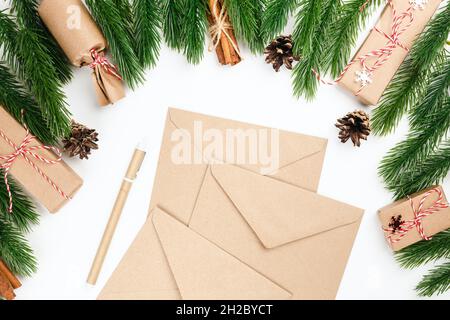 weihnachten flach legen aus Stapel von Handwerk Umschläge umrahmt mit Fichtenzweigen, Zapfen und Geschenke Stockfoto