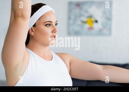 Junge Sportlerin in Übergröße im Stirnband-Training zu Hause Stockfoto