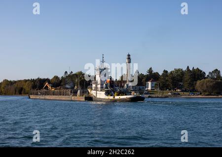 Ein großer See Barge in einen Kanal durch einen Leuchtturm. Stockfoto