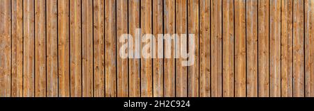 Braune Holzwand mit dunklen Zwischenräumen zwischen den vertikalen Brettern Stockfoto