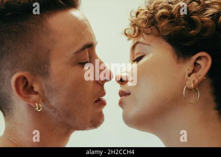 Ein romantisches Paar, das sich küsst. Liebevolles junges queeres Paar, das mit geschlossenen Augen dicht beieinander steht. Junge LGBTQ+ Paare teilen Stockfoto