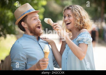 Ein Paar isst in spielerischer Haltung Eiscreme von Angesicht zu Angesicht Stockfoto
